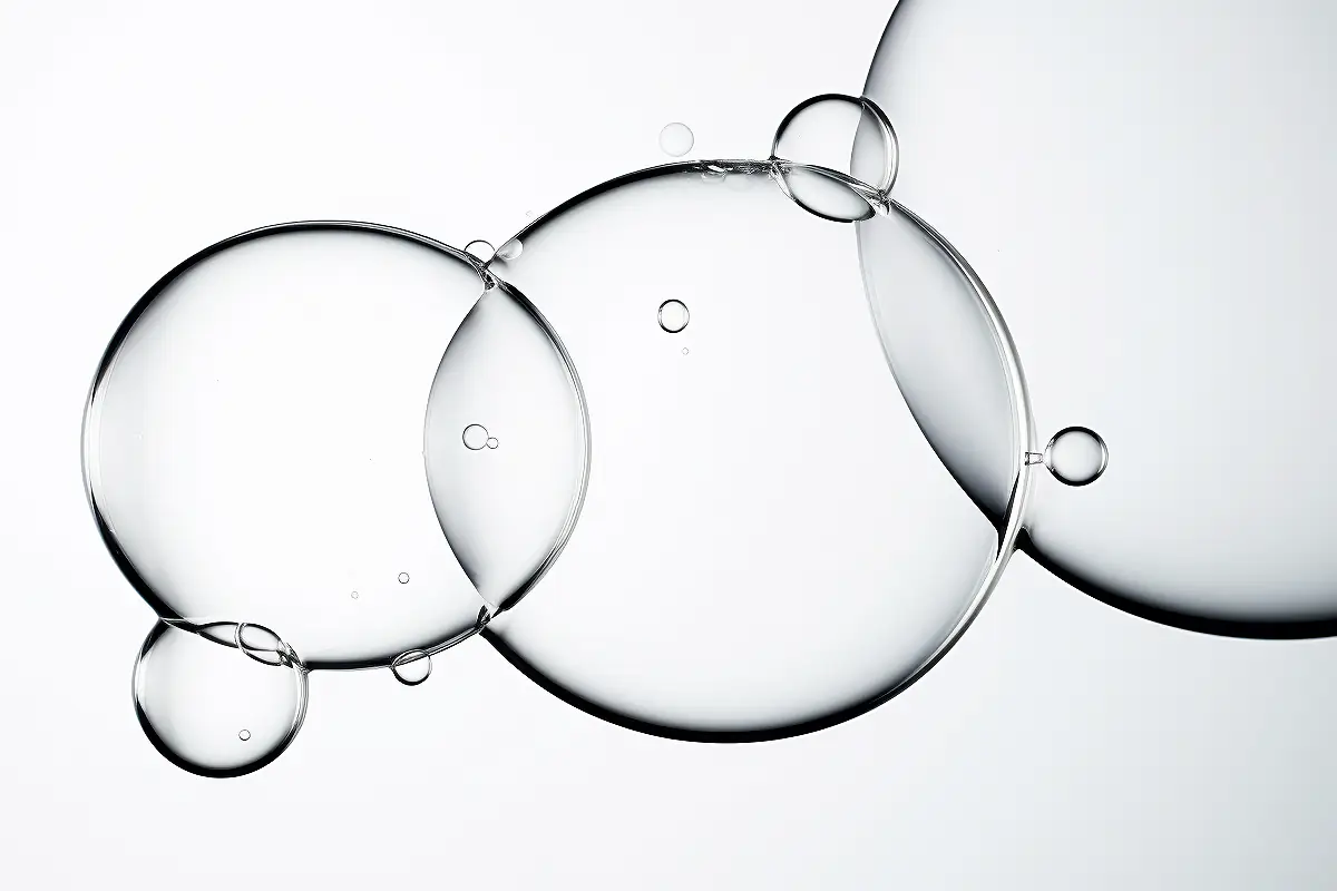 Transparent microbubbles representing microencapsulation technology, used to stabilize tranexamic acid and vitamin C in skincare formulations