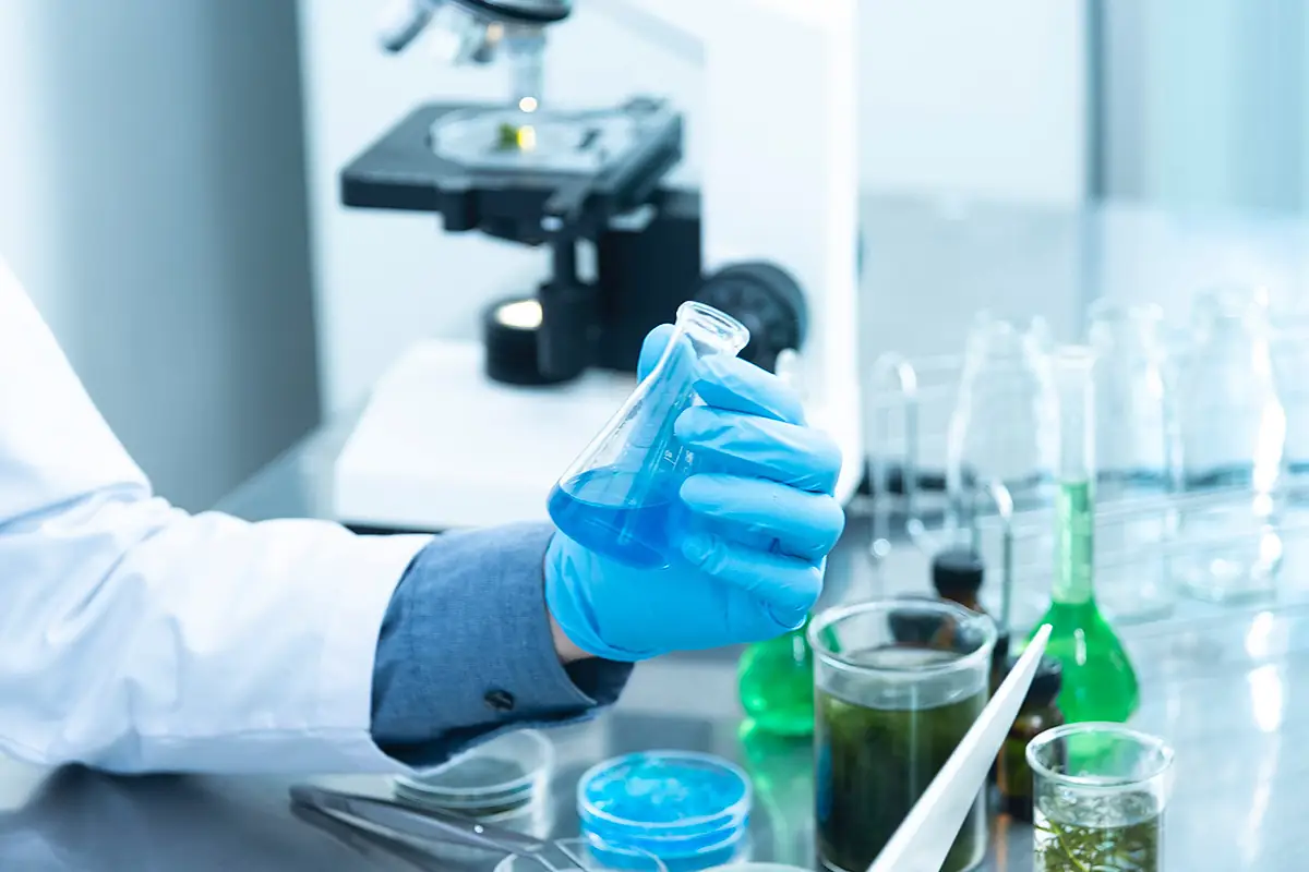 Cosmetic chemist in lab coat testing microencapsulated 377 formula, ensuring stability and efficacy for OEM manufacturing.