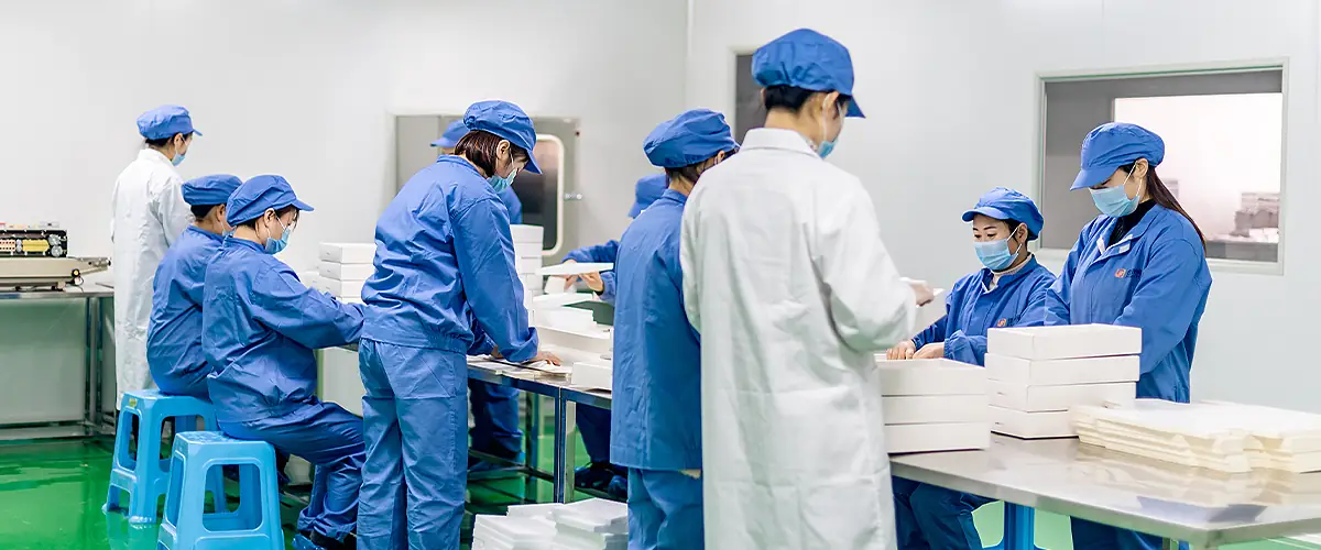 Factory team handling skincare product packaging and assembly in clean workshop