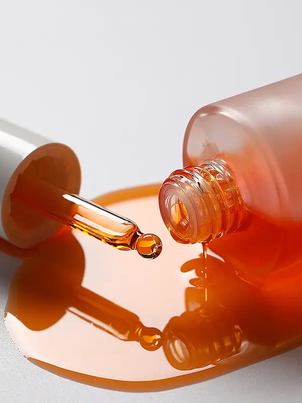 Close-up of serum dropper with orange high-potency serum for private label skincare