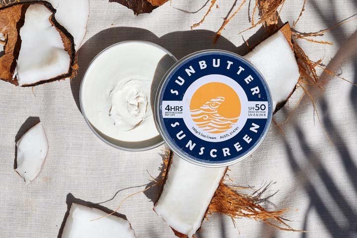 Image of Sunbutter SPF 50 sunscreen tin with cream texture and coconut pieces, representing reef-conscious sunscreen, natural SPF, and sustainable sun care products
