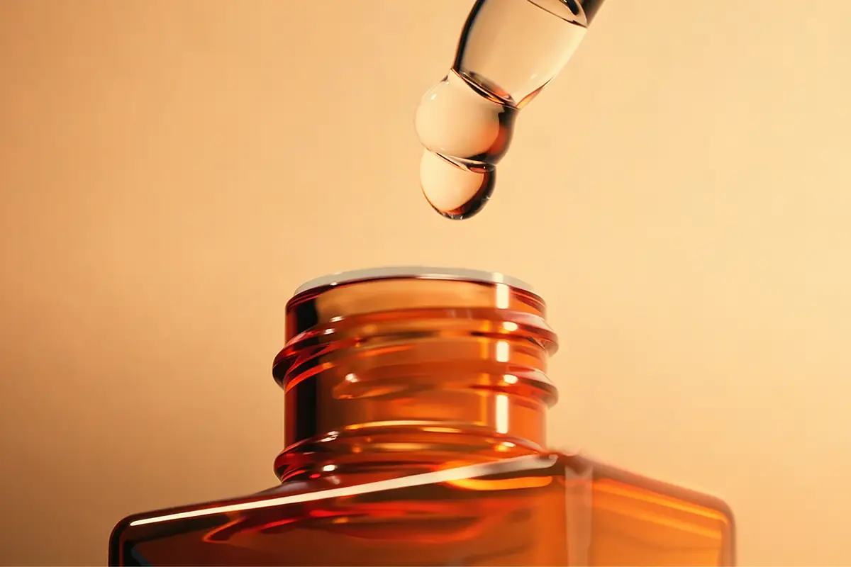 Amber dropper bottle with hair oil texture showing packaging compatibility for private label scalp oil products