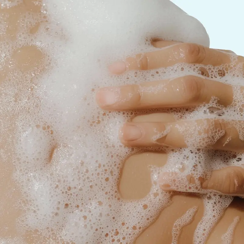 Foaming body scrub texture on wet skin for shower cleansing and exfoliation routine